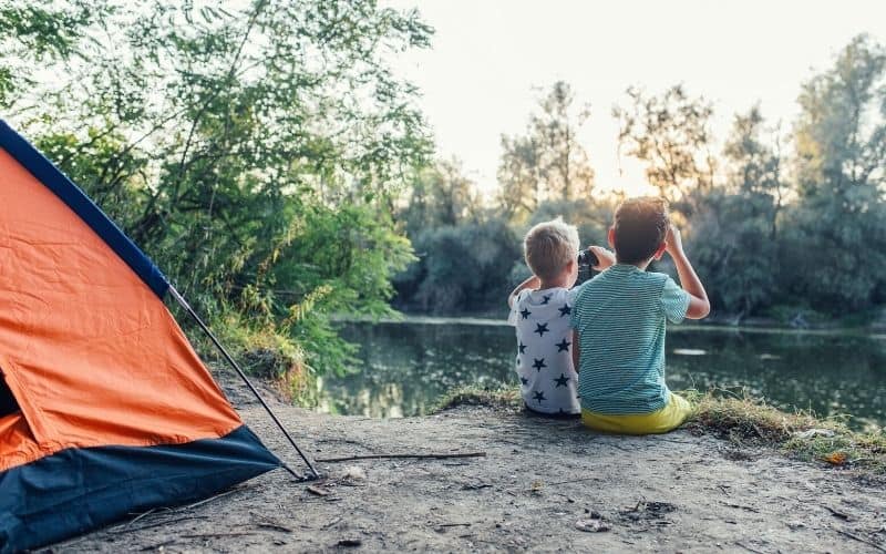 kids bird watching beside their tent