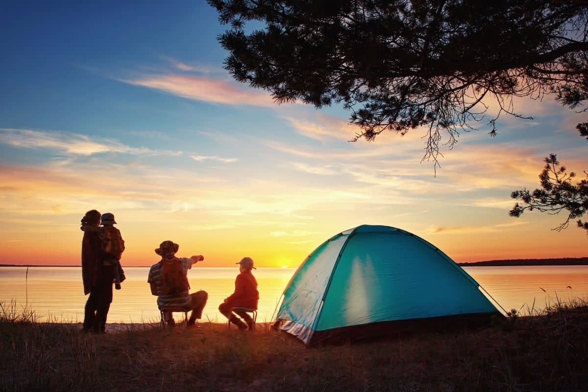 Family camping beside a lake at sunset