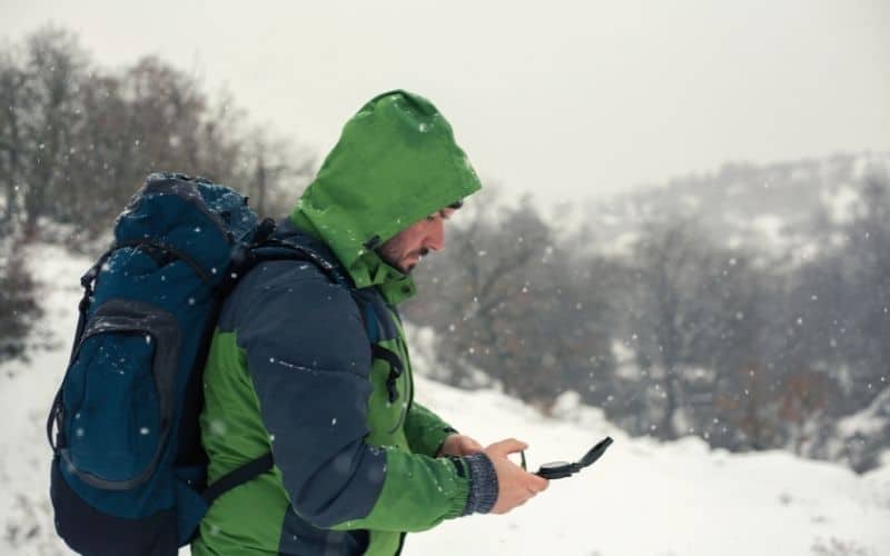 hiker in snow checking bearing