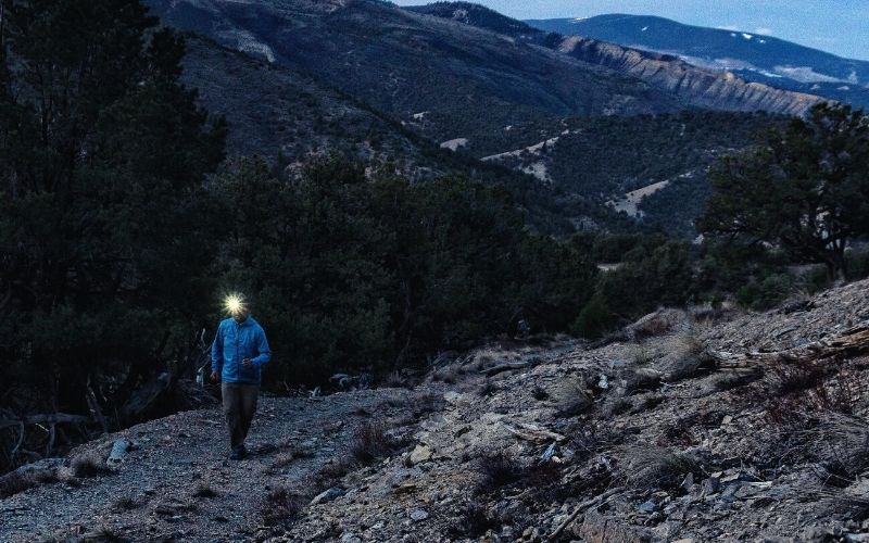 Hiker wearing headlamp hiking up rocky mountains