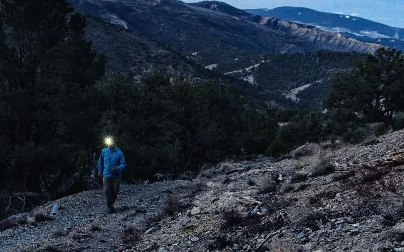 Hiker wearing headlamp hiking up rocky mountains