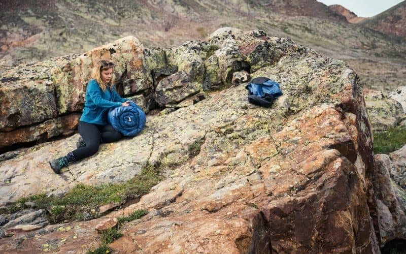 Female Backpacker packing away synthetic sleeping bag