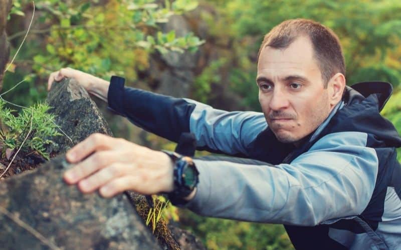 Man climbing rock face with hiking watch on wrist