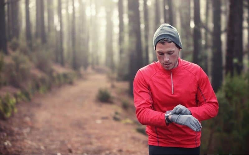 Trail runner looking at the heart rate monitor on his hiking watch