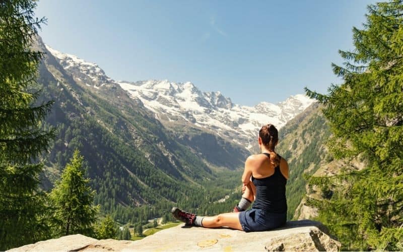 Woman sitting on cliff edge looking out over mountains