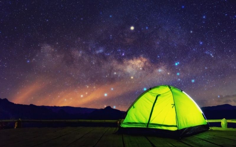 Lit up tent under a starry sky at night