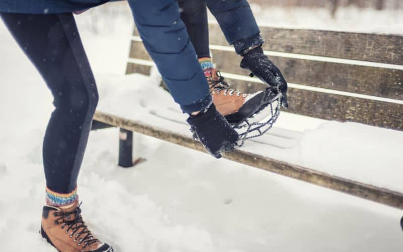 Woman wearing leggings and putting on cleats in the snow