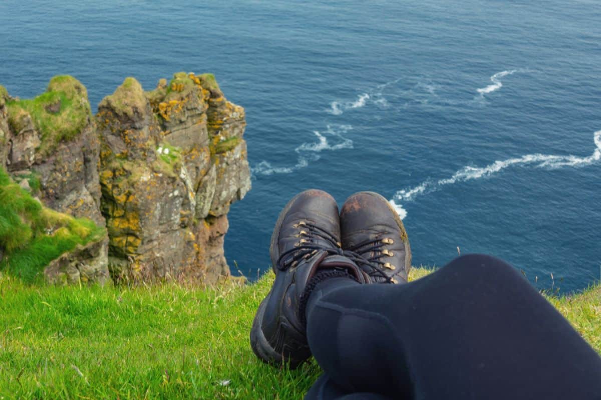Hiker sitting on clifftop wearing leggings and hiking boots