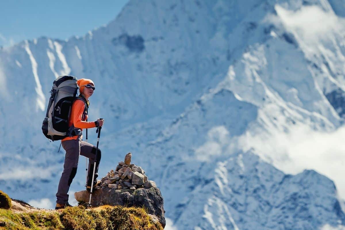 Woman wearing backpack standing at top of snowy mountains