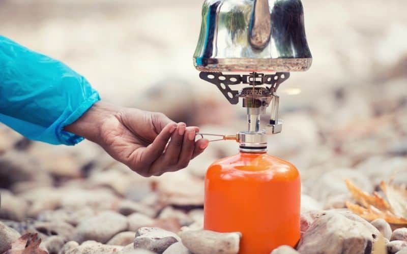 Camper adjusting the gas flame regulator on a camping stove