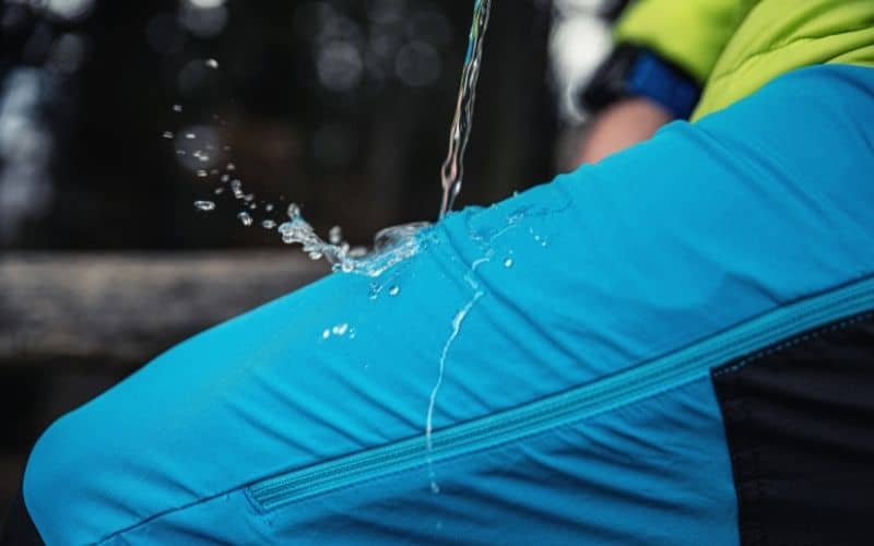 Person pouring water on waterproof rain pants