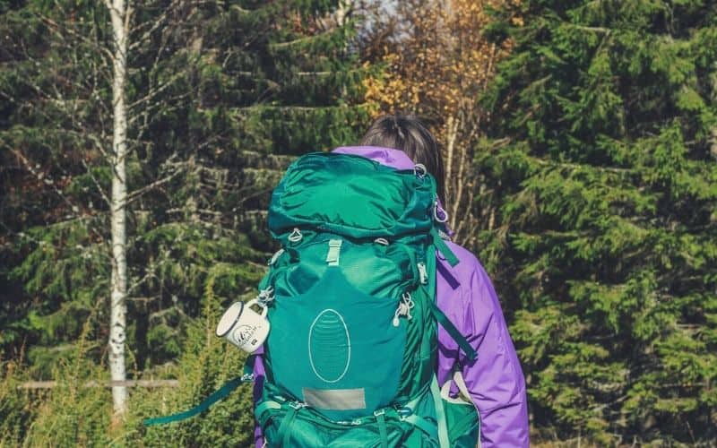 backpacker with Osprey backpack walking through forest