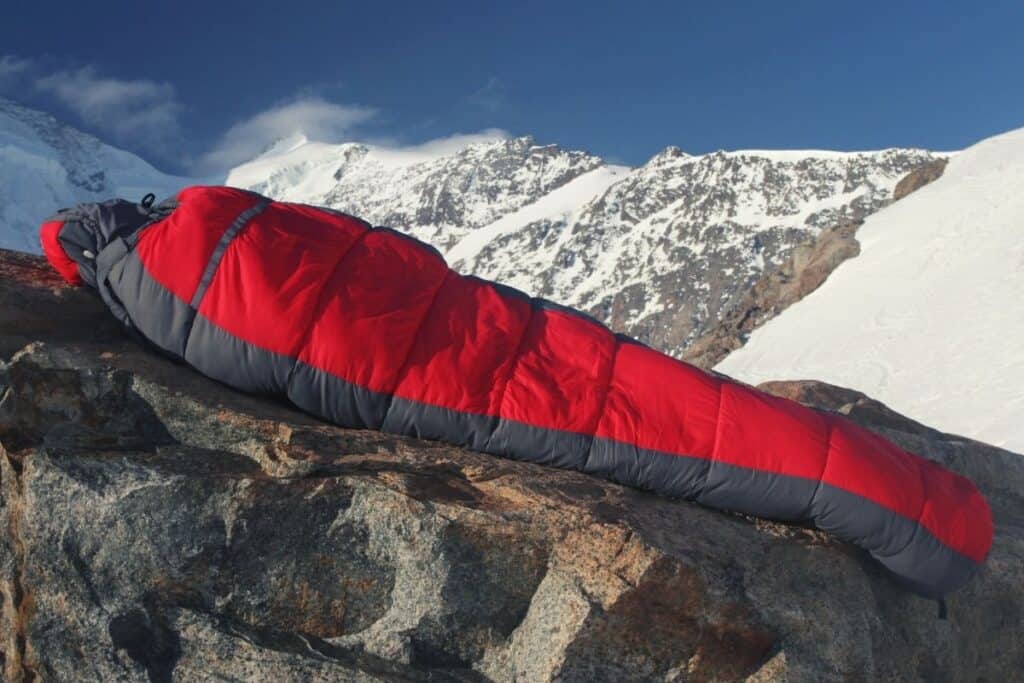 Sleeping bag laid out on rocks in front of snowy mountains