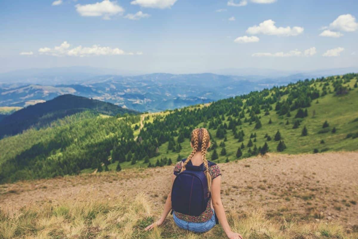Woman wearing small backpack looking out over hills