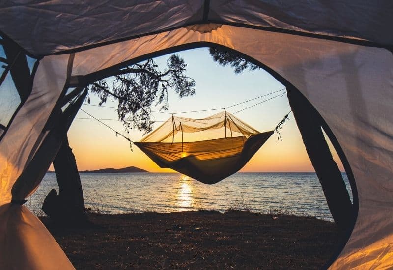 View of sunset behind hammock from inside a tent