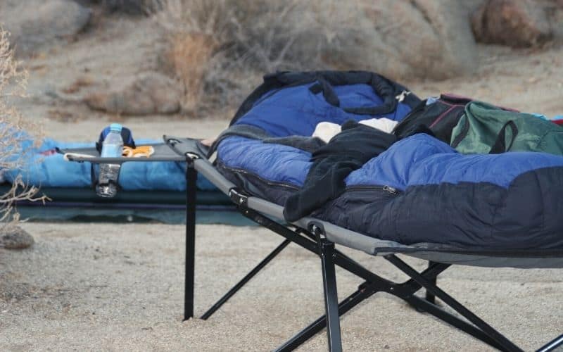 Camping cots with sleeping bags on top sitting outside