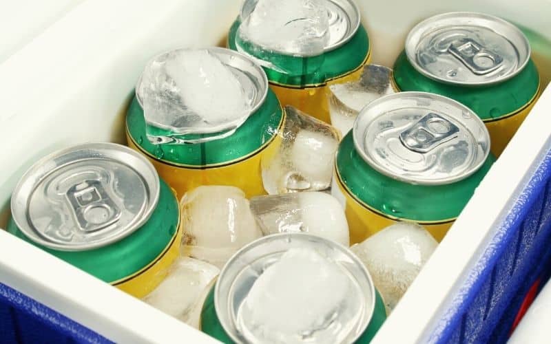 Cans of drink surrounded by ice in a chiller