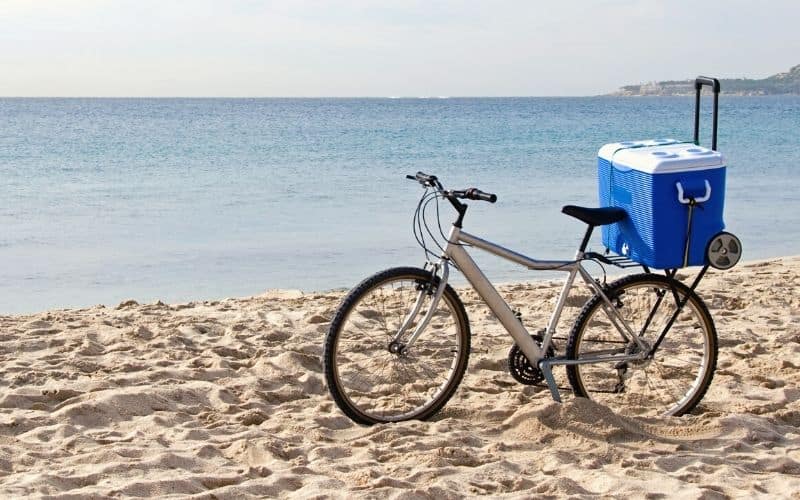 Cooler box sitting on the back of a bicycle on a beach