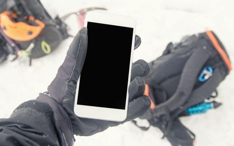 Gloved hand holding a phone in the snow