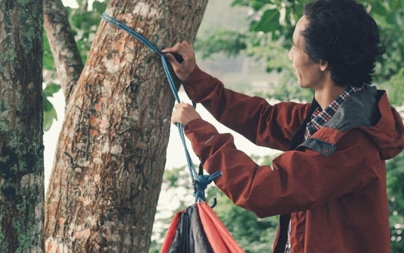 Man hanging hammock to tree with whoopie sling suspension