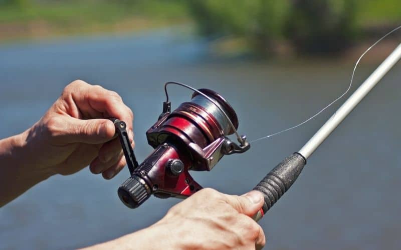 Man holding baitcasting fishing pole over water