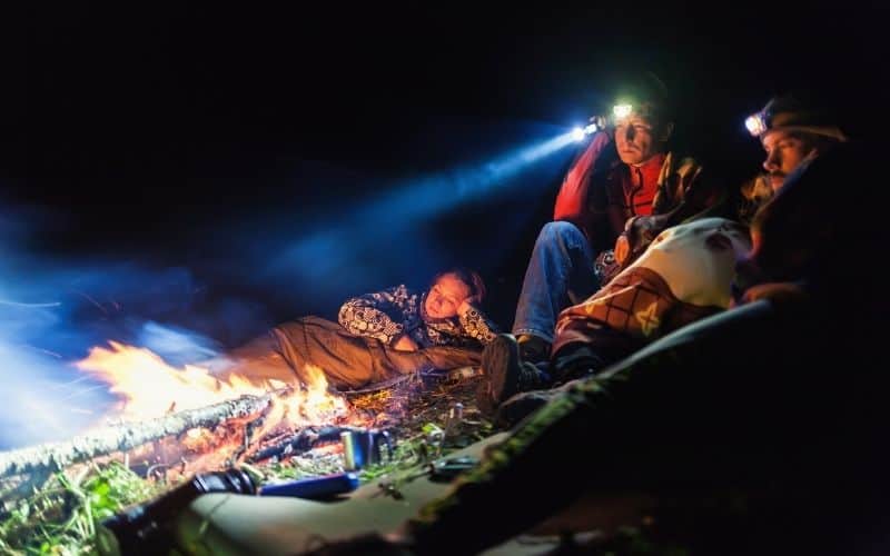 People wearing headlamps around a campfire
