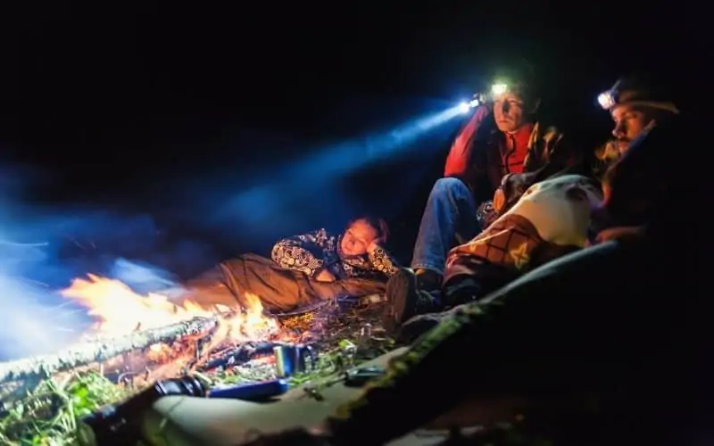People wearing headlamps around a campfire
