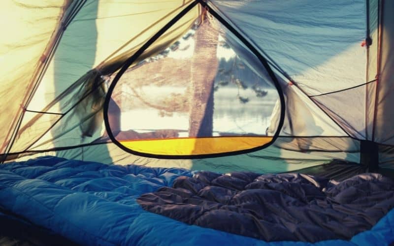 Sleeping bag in tent looking out on lake