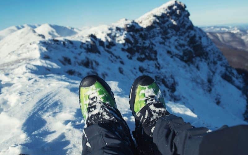 View of resting feet wearing ice boots at the top of a snowy mountain