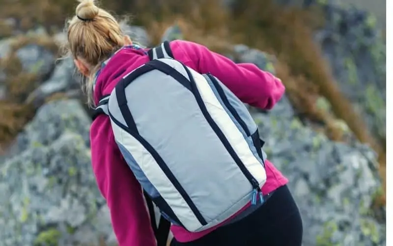 Woman carrying daypack with zippered access to main compartment