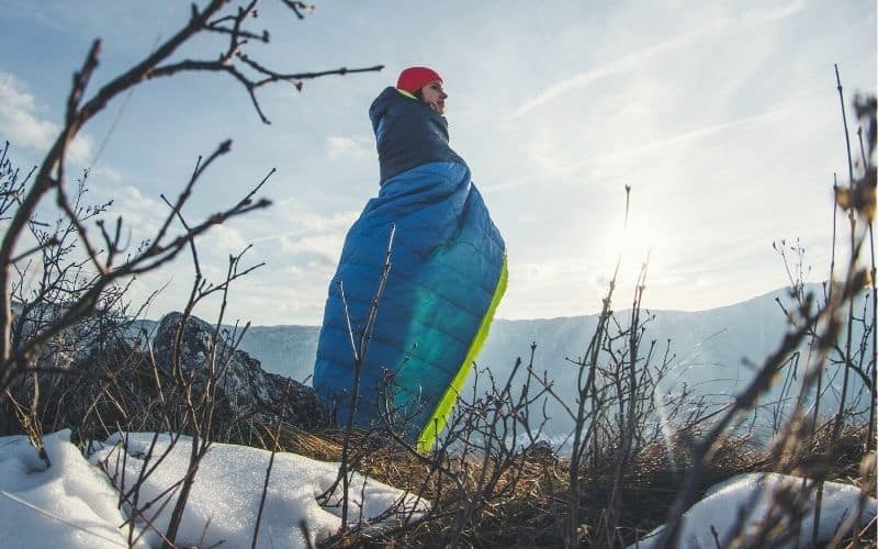 Woman standing in sleeping bag in the snow