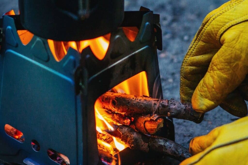 Close up of a person feeding wood into a camping wood burning stove