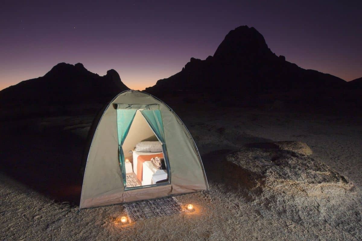 Tent lit up at night with camping cot inside