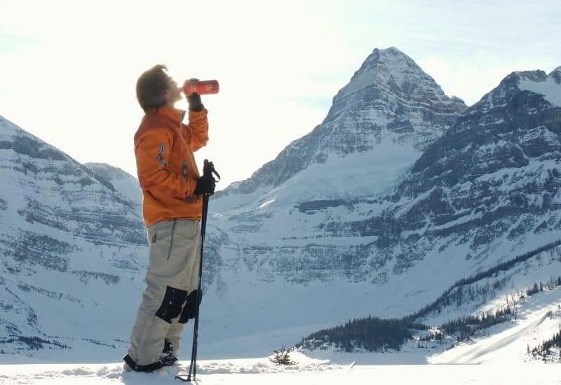 Man drinking out of water flask on a snowy mountain top