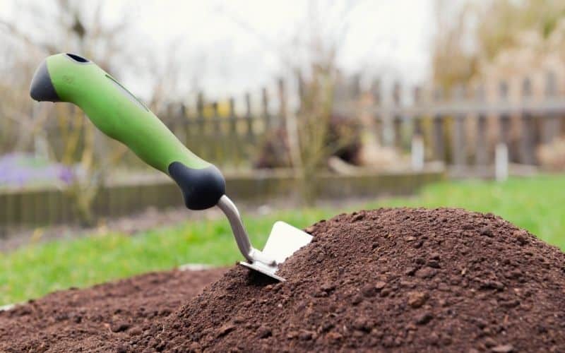 Ergonomic handle of garden trowel sticking out of soil