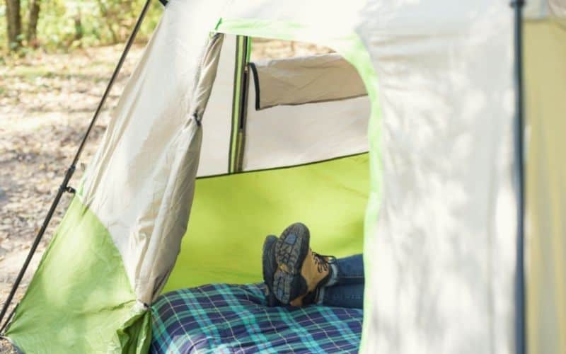 Feet on camping bed showing through tent door