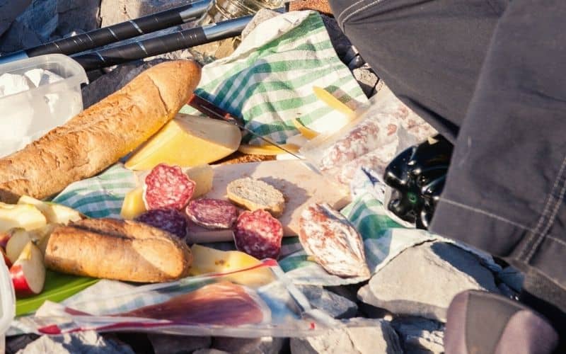 Hiker having salami and bread picnic
