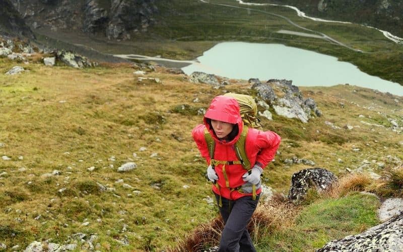 Hiker hiking uphill with rain jacket on and her hood up