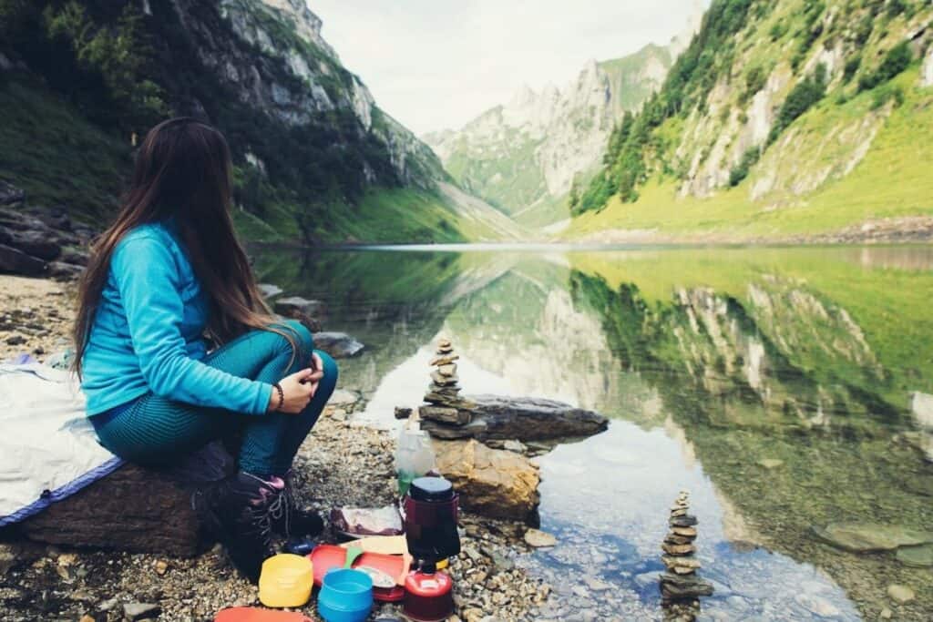 Women sitting in front of a lake and mountains eating her lunch