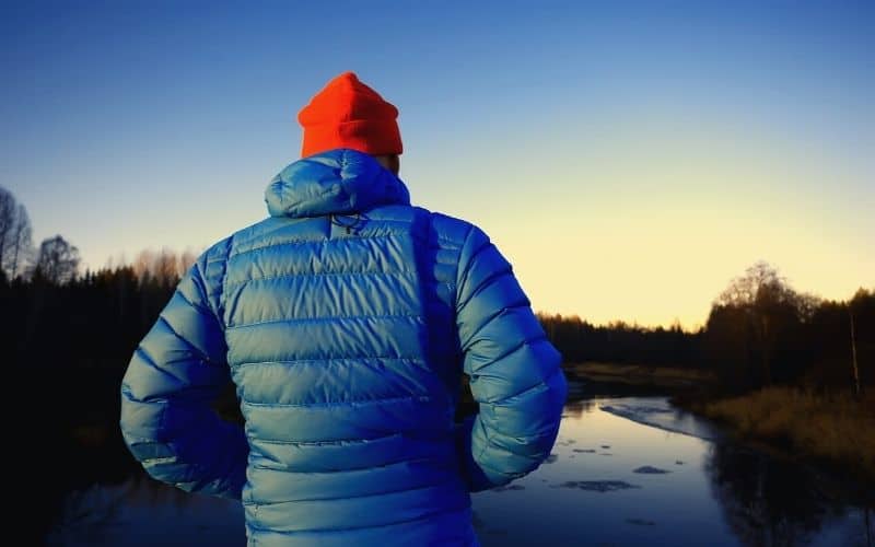 Man looking at a lake wearing a down jacket