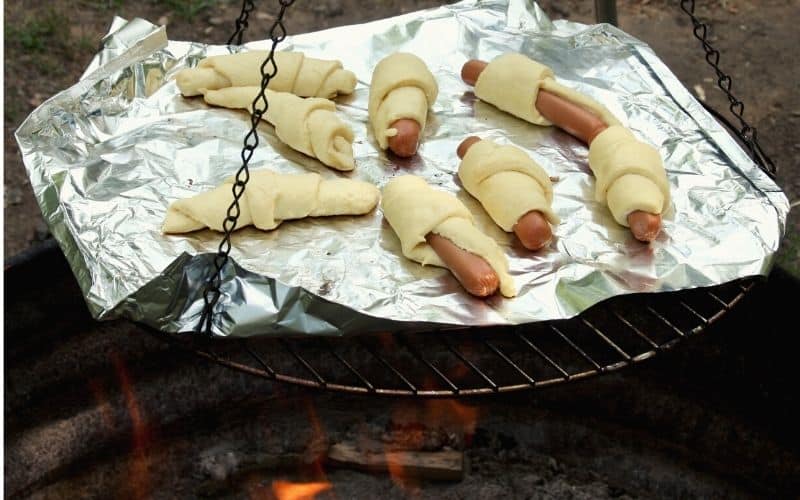Pigs in blankets cooked over a campfire