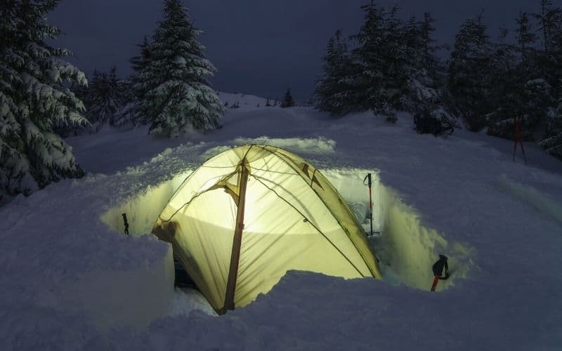 Tent pitched inside a snow dugout creating an all-around windbreaker