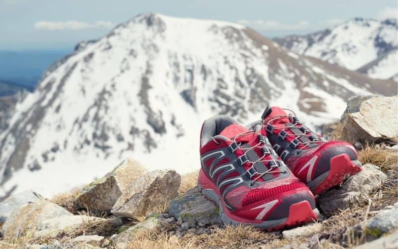 Trail running shoes sitting in front of a snowy mountain