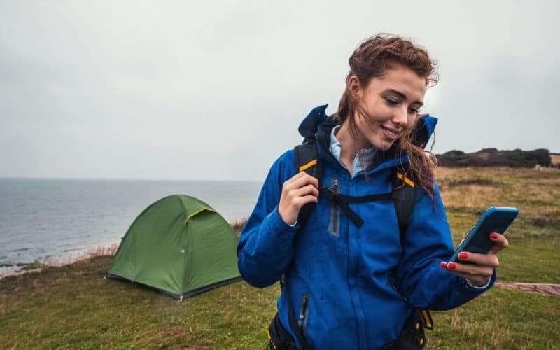 Woman camping and looking at her phone