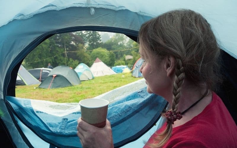 Woman sitting in tent looking out to campsite