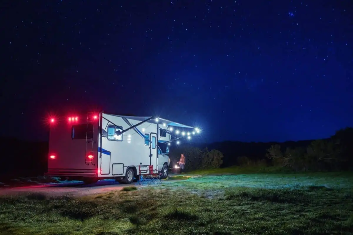 Motorhome with string lights under awning parked under a starry sky