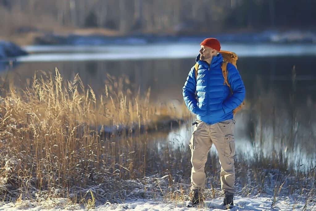 Man wearing down jacket standing in front of lake