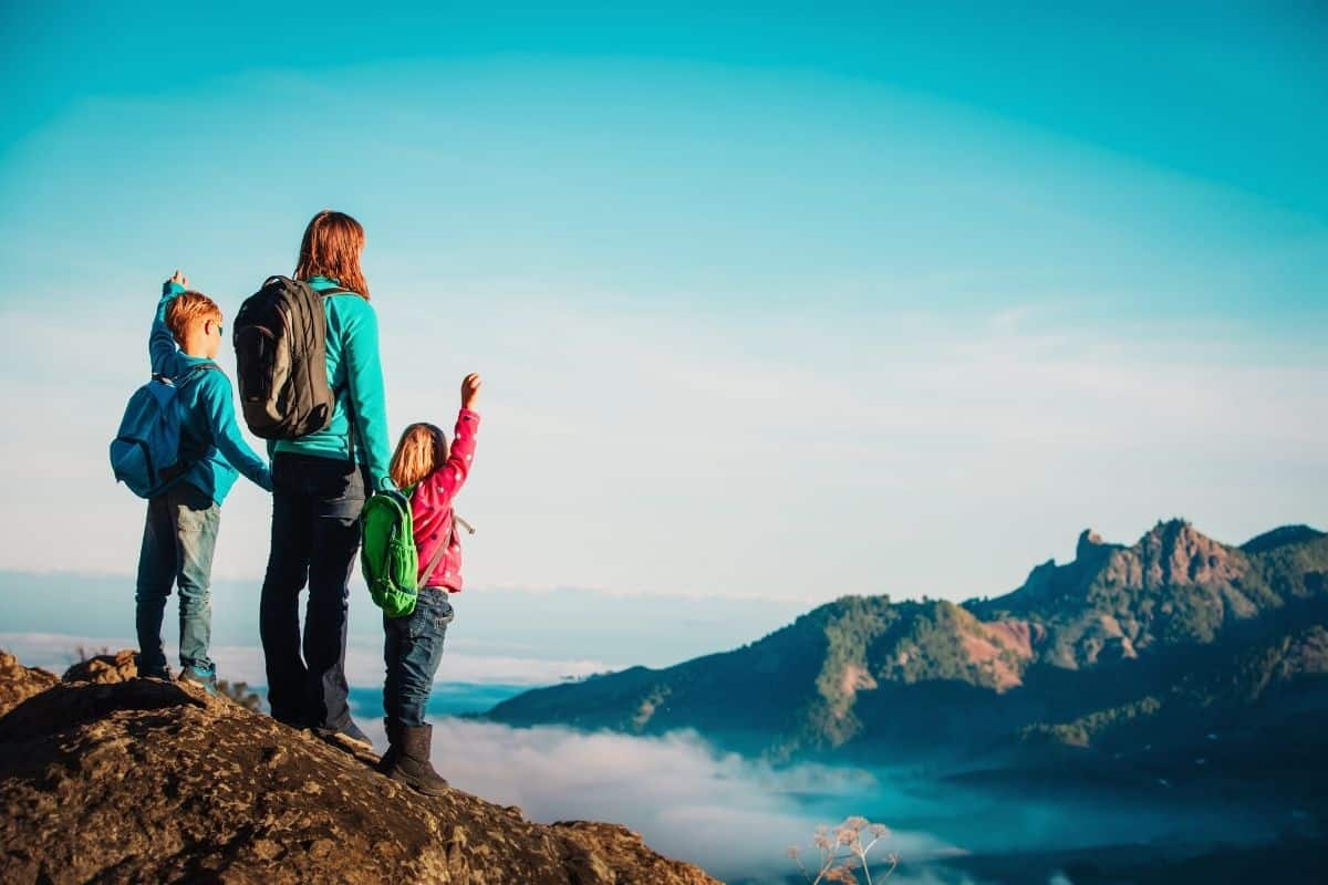 Kids and a parent wearing backpacks on top of a mpuntain