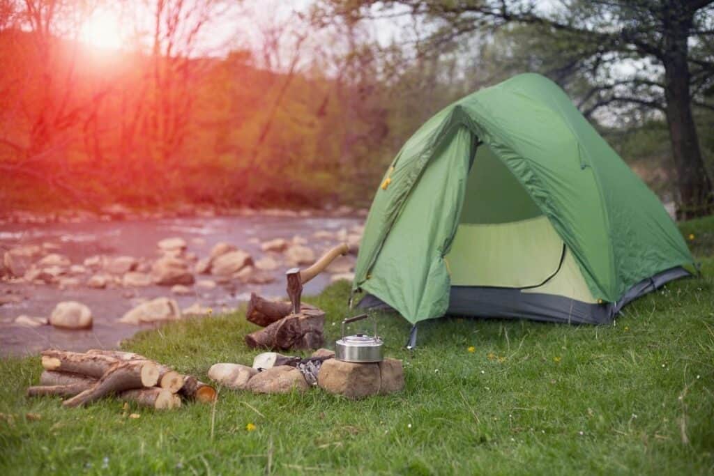 Tent pitched beside a river with camping essentials outside