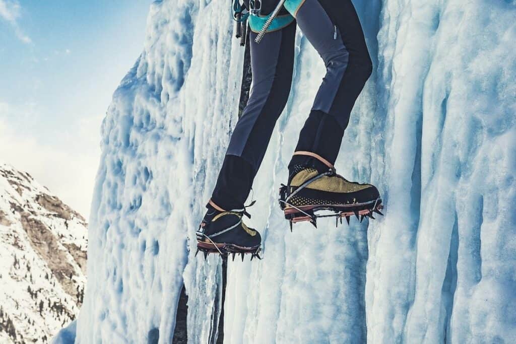 Person climbing up an icy waterfall wearing crampons